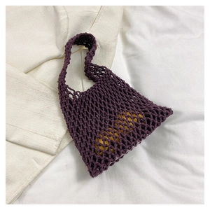 Detailed close-up of a deep purple hand-woven mesh tote bag on a beige blazer background