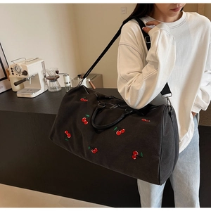 Detail of black canvas tote bag featuring red cherry embroidery and dual handles