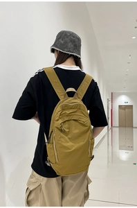 Detailed back view of a mustard yellow waterproof nylon backpack on a female model