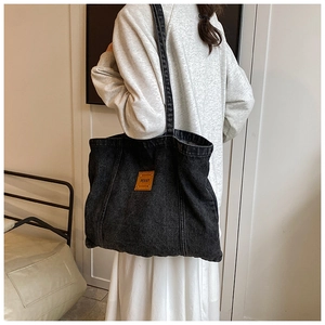 Detailed back view of a large denim tote bag featuring a brown Penny leather patch
