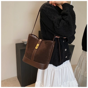 Detail view of retro faux suede crossbody bag with golden twist-lock closure on model