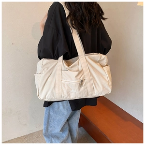 Detail of beige nylon tote bag with VEILA embroidery and multi-pocket design on the back