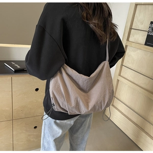 Detail view of large taupe nylon crossbody bag featuring stylish side drawstring ruching
