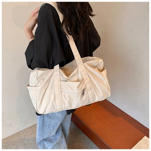 Detail of a large cream nylon tote bag with Bella embroidery and multiple side pockets