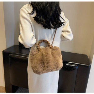 Detailed close-up of camel plush crossbody bag with woven handles on a model