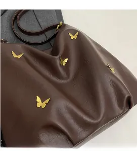 Detail of dark brown PU leather bag with soft texture and golden butterfly ornaments