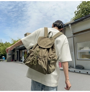Detail of olive green nylon backpack with drawstring flap closure and side pockets