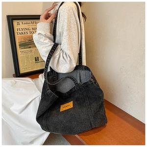 Detail shot of black washed denim tote bag with long shoulder strap and orange logo tag