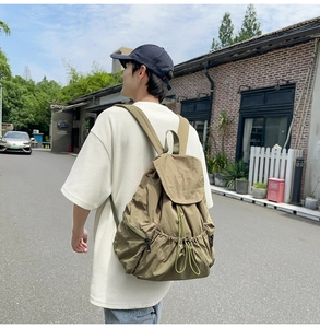 Outdoor lifestyle shot of a khaki nylon drawstring backpack with pleated texture