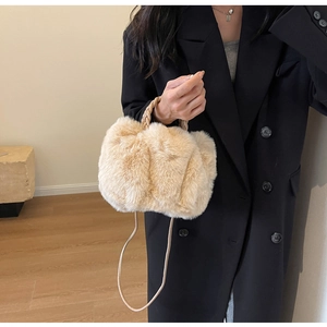 Detail view of beige faux fur handbag with woven handle and slim shoulder strap