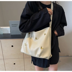 Detail of beige PU leather tote with golden 3D butterfly accents and fine shoulder strap