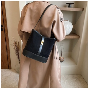 Detail view of black faux suede bucket bag featuring a premium gold twist lock closure