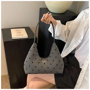 Dettaglio della borsa sottobraccio in denim grigio con pois neri e fiocco argento