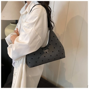 Dettaglio della borsa hobo grigio scuro a pois con fiocco d'argento e tracolla in pelle