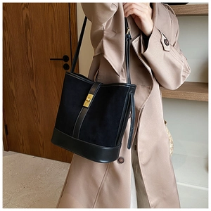 Detail of a black bucket bag in suede and smooth leather with golden clasp hardware