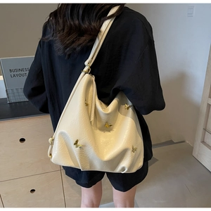 Close-up of cream PU leather shoulder bag featuring decorative gold 3D butterflies