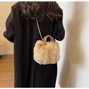 Plush faux fur crossbody bag in beige with woven leather handles on a black coat