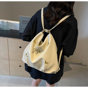 Detail of creamy white PU leather backpack featuring golden butterfly metal decorations