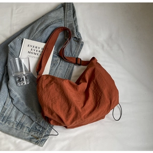 Minimalist rust red nylon crossbody bag with adjustable strap and drawstring detail