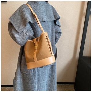 Detail view of suede and smooth leather bucket bag with golden metallic clasp closure