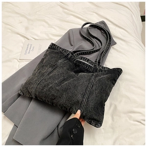 Washed black denim tote bag with soft structure shown on a grey blazer for casual wear