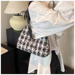 Dettaglio borsa hobo con motivo a scacchi bianco e nero, stampa a cuori e fiocco argento