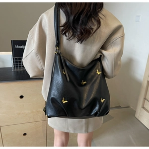 Detail of black PU leather hobo bag featuring five golden 3D butterfly metal ornaments