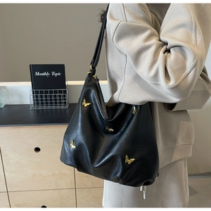 Close-up of black PU leather bag with elegant golden butterfly hardware ornament