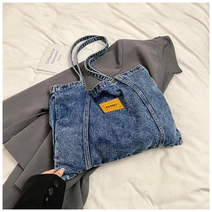 Minimalist washed denim tote bag with yellow logo label and stylish shoulder straps