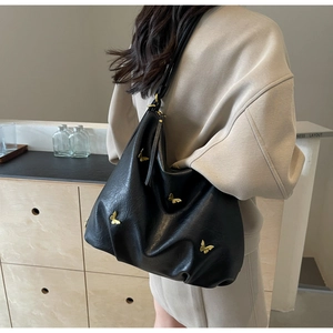 Detail of black PU leather hobo bag with a decorative gold metal 3D butterfly ornament