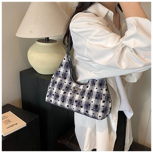 Dettaglio borsa hobo a scacchi con cuori e fiocco argento indossata da modella