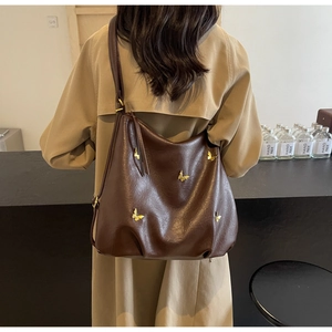 Detail of vintage brown PU leather bag with golden butterfly accents on a beige coat