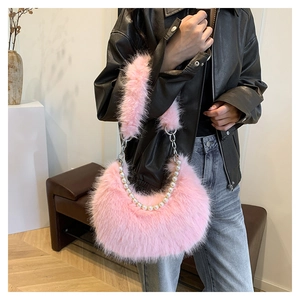 Détail d'un sac à bandoulière en peluche rose avec chaîne perlée sur un mannequin