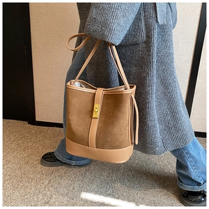 Detail of a brown bucket bag showing suede texture, leather拼接 and a gold metal twist lock