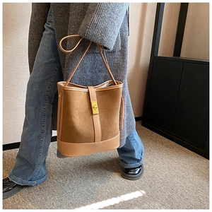 Detailed view of brown faux suede bucket bag featuring a gold twist lock and leather strap