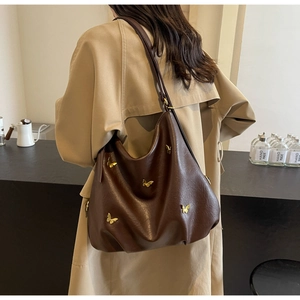 Detail of dark brown PU leather tote bag with vintage golden butterfly metal accents