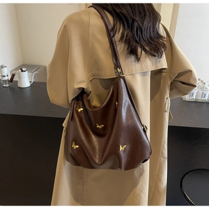 Detailed view of dark brown PU leather tote with 3D golden butterfly metal accents
