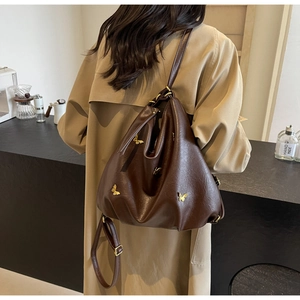 Detailed view of dark brown PU leather backpack with golden butterfly metal ornaments