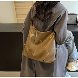 Brown PU leather tote bag with gold butterfly accent shown on a model's shoulder