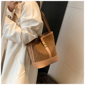 Detail of suede bucket bag featuring brown contrast stitching and golden turn-lock closure