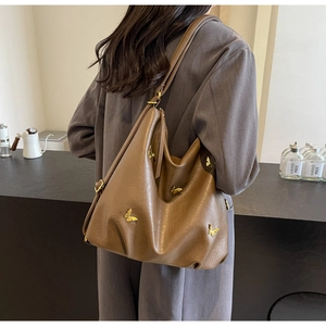Detail of a brown PU leather Hobo bag featuring gold butterfly ornaments and a wide strap