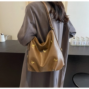 Detail of dark brown PU leather hobo bag with golden butterfly metal ornaments