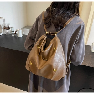 Detail view of brown PU leather backpack with butterfly ornaments on model in a cafe