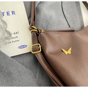 Detail of brown litchi pattern PU leather bag with golden butterfly ornament