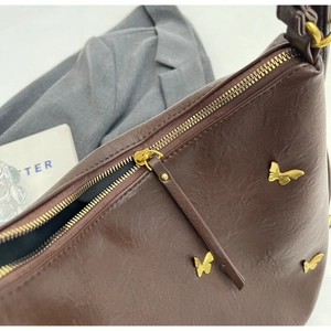 Detail view of brown PU leather bag featuring gold butterfly accents and metal zipper