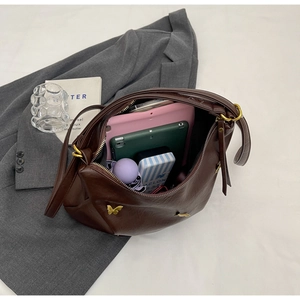 Macro detail of spacious coffee PU leather hobo bag with gold butterfly and daily essentials