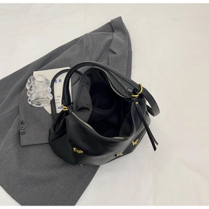 Detail view of black PU tote bag interior with gold butterfly clasp and zipper closure