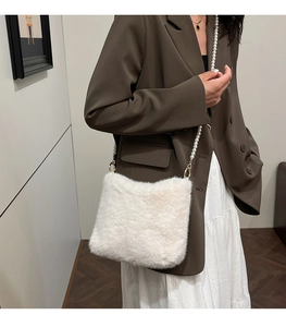 Détail du sac à bandoulière en peluche crème avec bandoulière perle sur blazer brun
