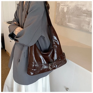 Deep brown glossy crescent shoulder bag with silver eyelet belt details shown on model