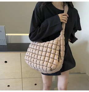 Detail view of a beige puffer bubble tote bag worn as a crossbody for daily commute